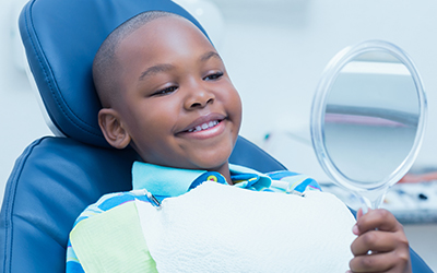 A young boy sitting in a dental chair smiling