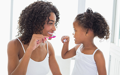 Mother and young girl brushing their teeth together