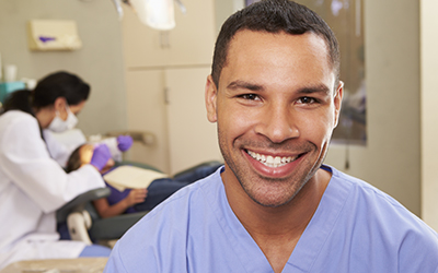 Up-close of dentist with the nurse and patient in the background