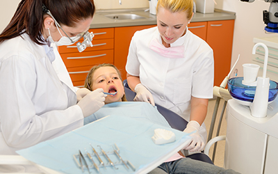 A dentist working on a child's mouth