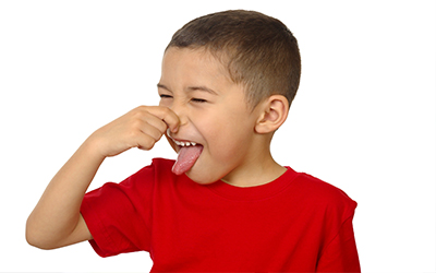 A young boy plugging his nose and sticking his tongue out