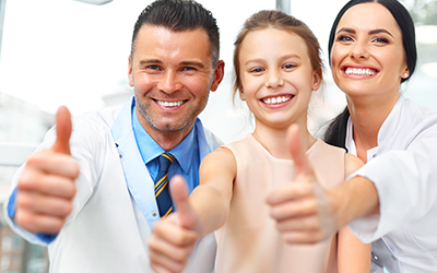 A daughter, dentist and mom smiling and giving a thumbs up